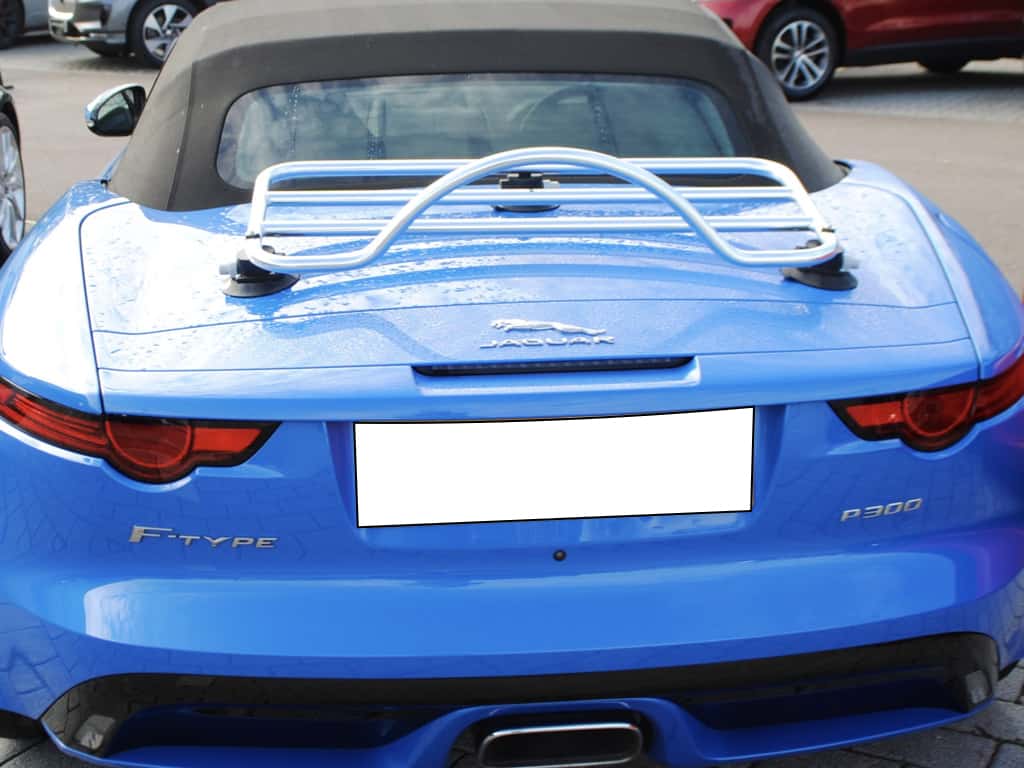 light blue jaguar f type p300 convertible with a chrome luggage rack fitted to the boot photographed from behind the car