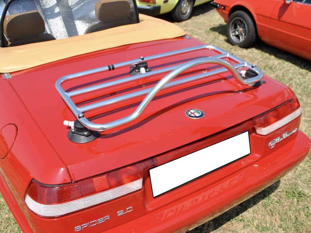 red alfa romeo spider 2.0 with a cream hood and a luggage rack fitted to the boot