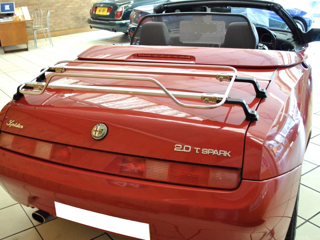 red alfa spider 916 in a car showroom with a stainless steel luggage rack fitted