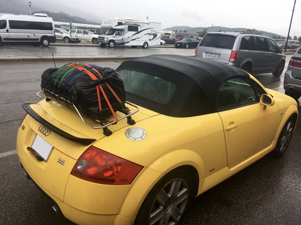 yellow audi tt convertible with a stainless steel luggage rack fitted with a black case on it