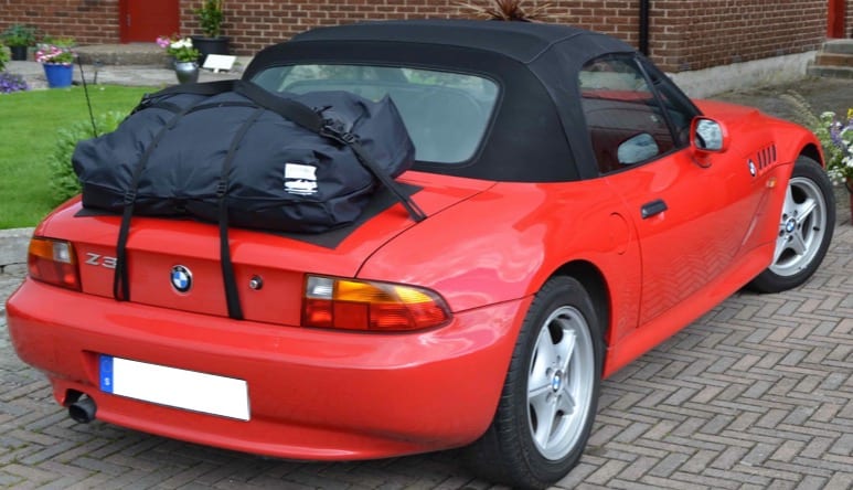 red bmw z3 with a boot-bag vacation luggage rack fitted on a drive next to a lwn