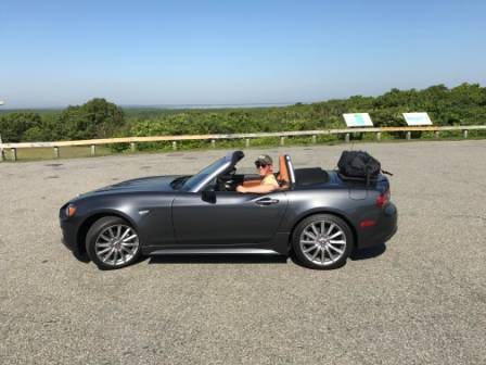 grey fiat 124 spider with the hood down and a boot-bag original luggage rack fitted