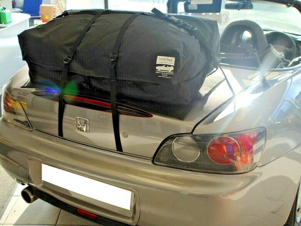 silver honda s2000 with a boot-bag vacation luggage rack fitted in a car showroom hood down.