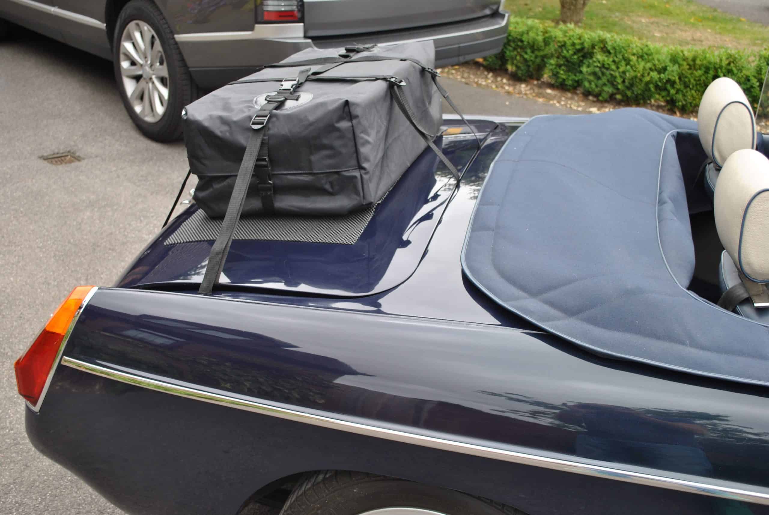 side view of a dark blue mgb with a boot-bag original luggage rack/bag fitted to the boot lid