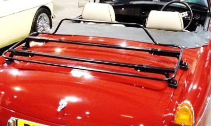 red mgb with the hood down and cream seats with a black luggage rack fitted to the boot