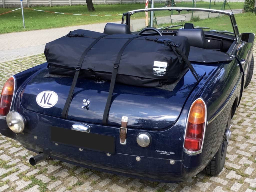 dark blue mgb with no rear bumper and the hood down and a boot-bag vacation luggage rack fitted