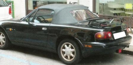 british racing green mazda mx5 mk1 with e black luggage rack fitted photographed on a street from the side