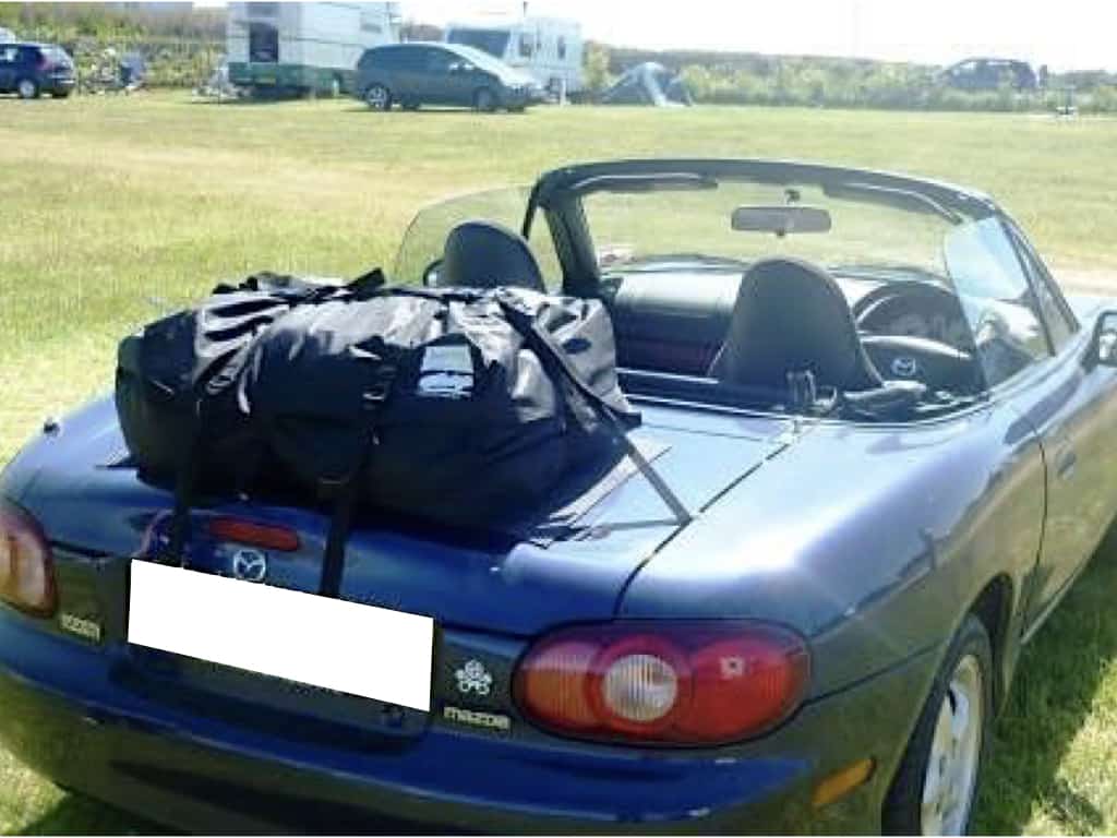 blue mazda mx5 in campsite on a sunny day hood down with a boot-bag original luggage rack fitted