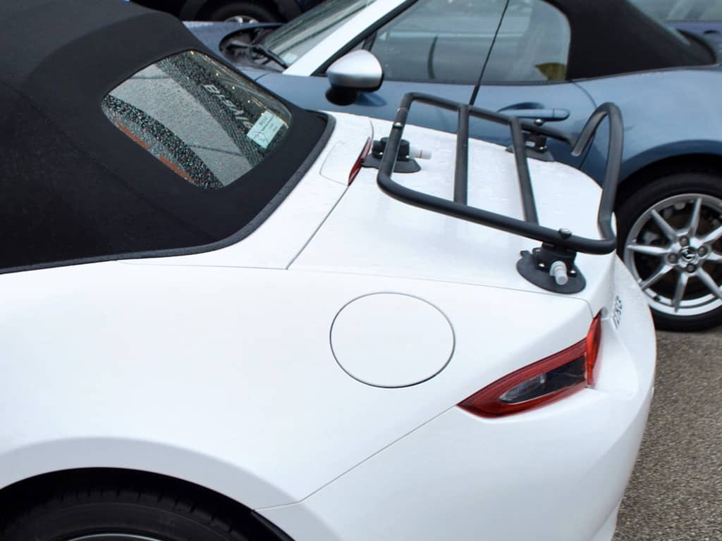 white mazda mx5 with a black hood and a revo-rack black luggage rack fitted on a rainy day