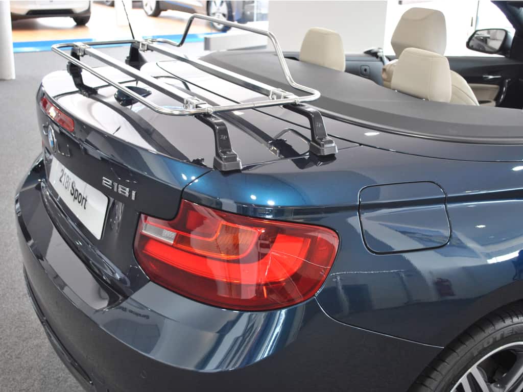 side view of a bmw 2 series convertible with a stainless steel luggage rack fitted in a bmw showroom hood down