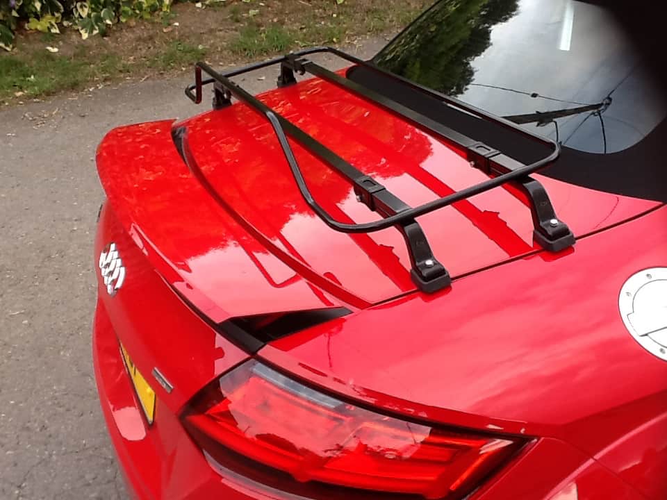 side view of a red audi tt convertible or roadster with a black luggage rack fitted