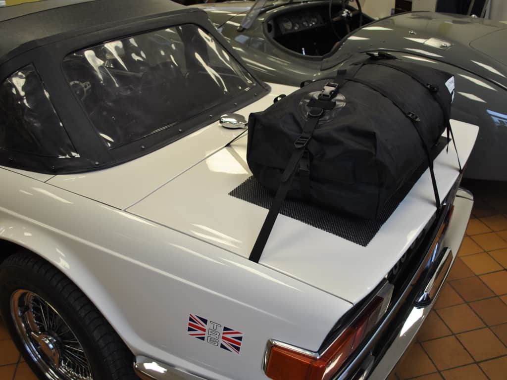 side view of a white triumph TR6 with a boot-bag luggage rack attached