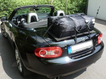 black mx5 mk3 with the hood down on a sunny day and a boot-bag original luggage rack fitted to the boot