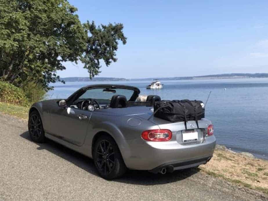silver mazda mx5 mk3 roadster coupe on a coastal road with the sea in the background and a bot-bag original luggage rack fitted