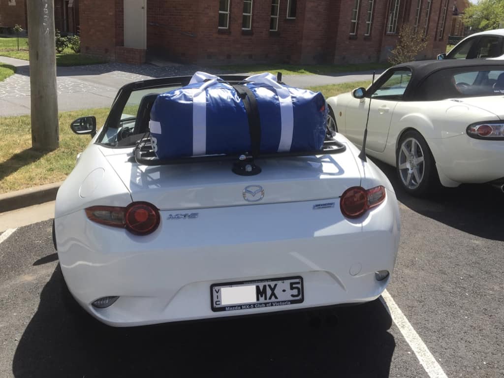 white mazxda mx5 mk4 with a revo-rack luggage rack fitted with a large blue holdall on it