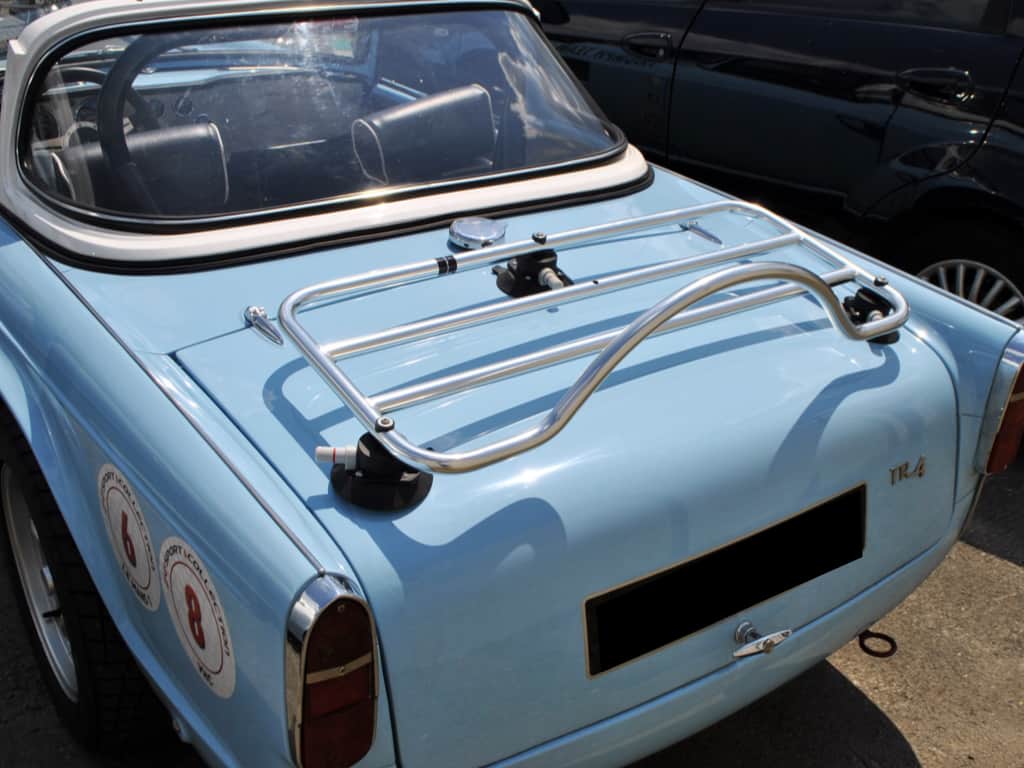 light blue triumph TR4 with a white hardtop and a chrome luggage rack fitted
