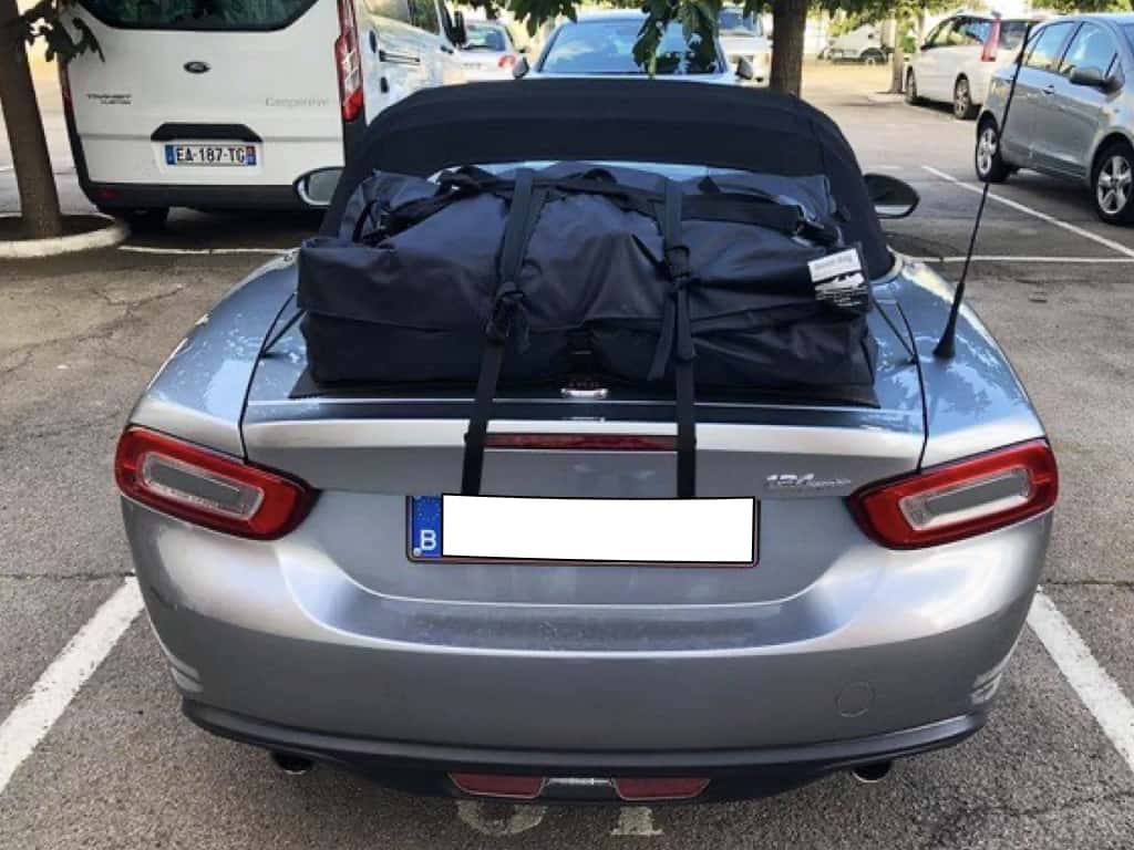 Silver grey fiat 124 spider with a boot-bag luggage rack fitted in a car park