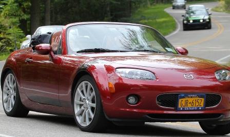 burgandy mazda mx5 on a twisty road with a boot-bag luggage rack fitted