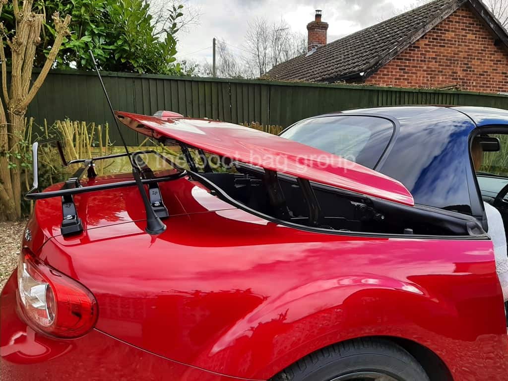 red mazda mx5 roadster coupe mk3 with a black luggage rack fitted and the roof operating 