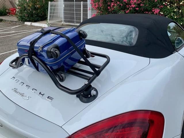 black luggage rack fitted to the boot lid of white porsche boxster carrying a blue suitcase