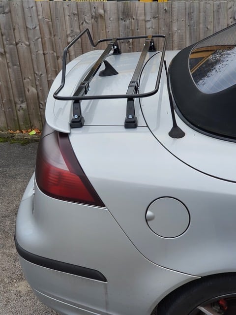 silver saab 93 convertible with a black luggage rack fitted photographed from the side