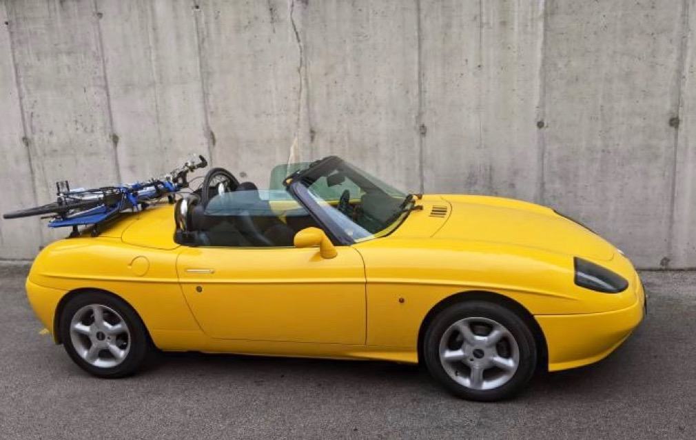 Yellow Fiat Barchetta with a luggage rack fitted carrying a bike