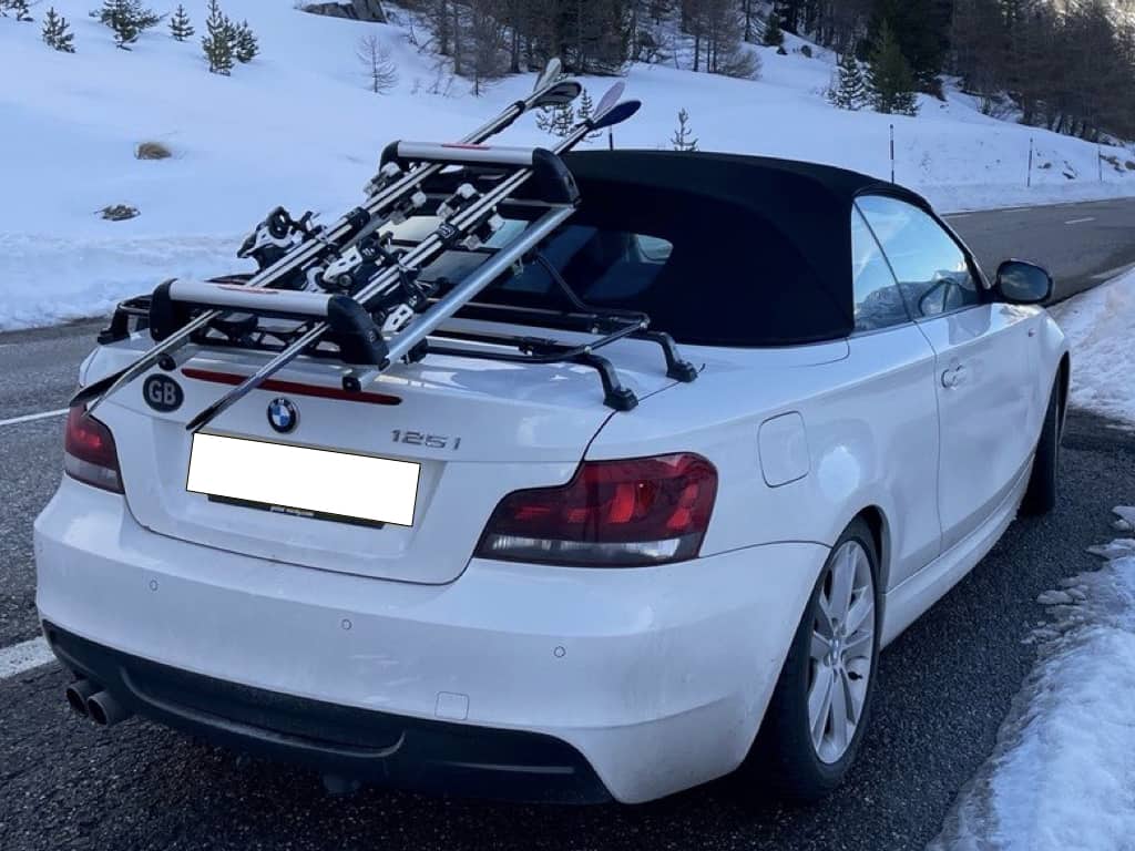 white bmw 1 series convertible on a mountain road with a luggage rack fitted carrying skis