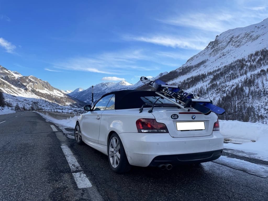 white bmw 1 series convertible with a luggage rack fitted carrying skis
