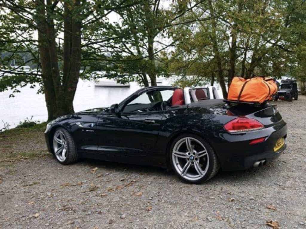 black bmw z4 e89 roof down next to a lake with a revo-rack black luggage rack fitted carrying a orange holdall.