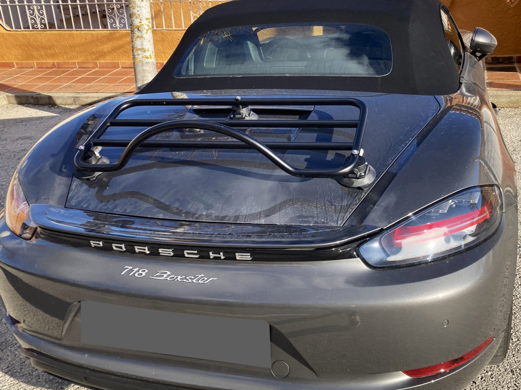 grey porsche boxster 718 with a revo-rack luggage rack fitted to the boot lid photographed from the rear on s sunny day