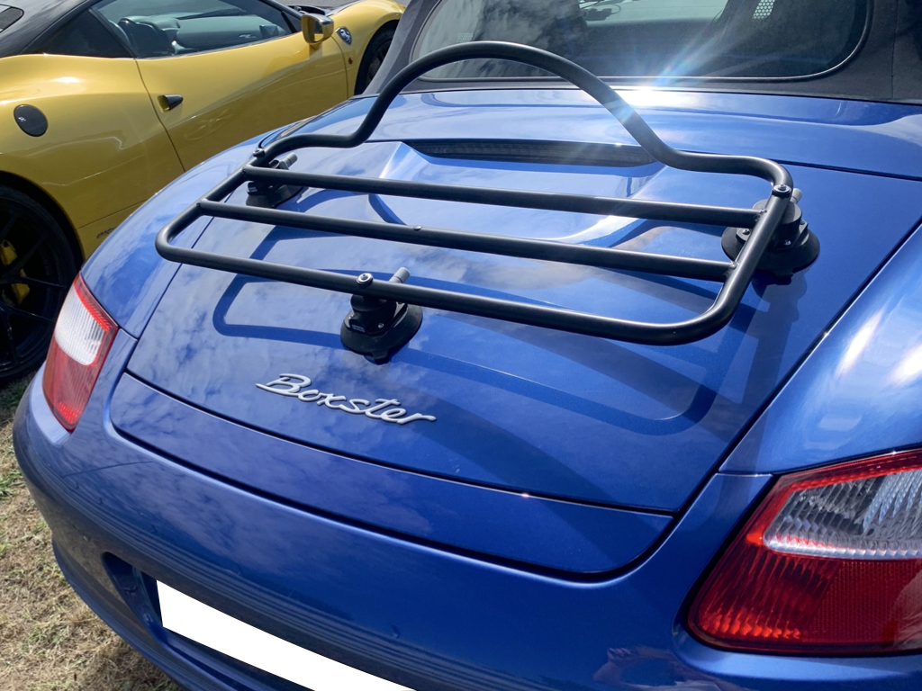 blue porsche boxster 987 with a black luggage rack fitted to the boot photographed from the rear