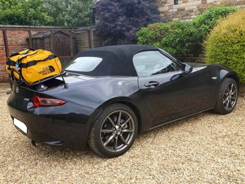 black mazda mx5 mk4 nd with a revo-rack luggage rack fitted carrying a large yellow north face holdall