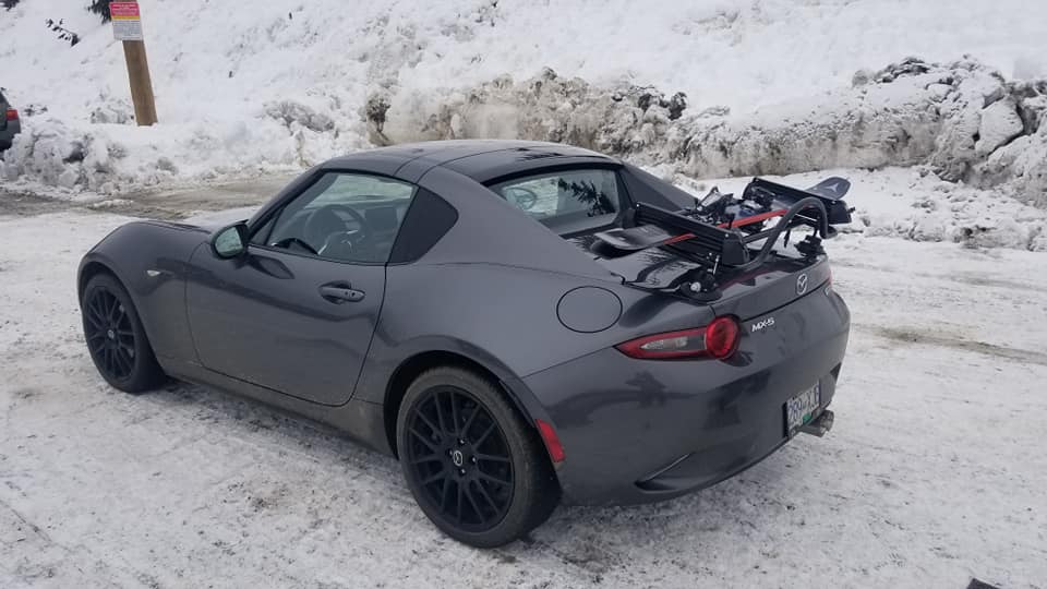 grey mazda mx5 rf with a boot rack fitted carrying ski's surrounded by snow
