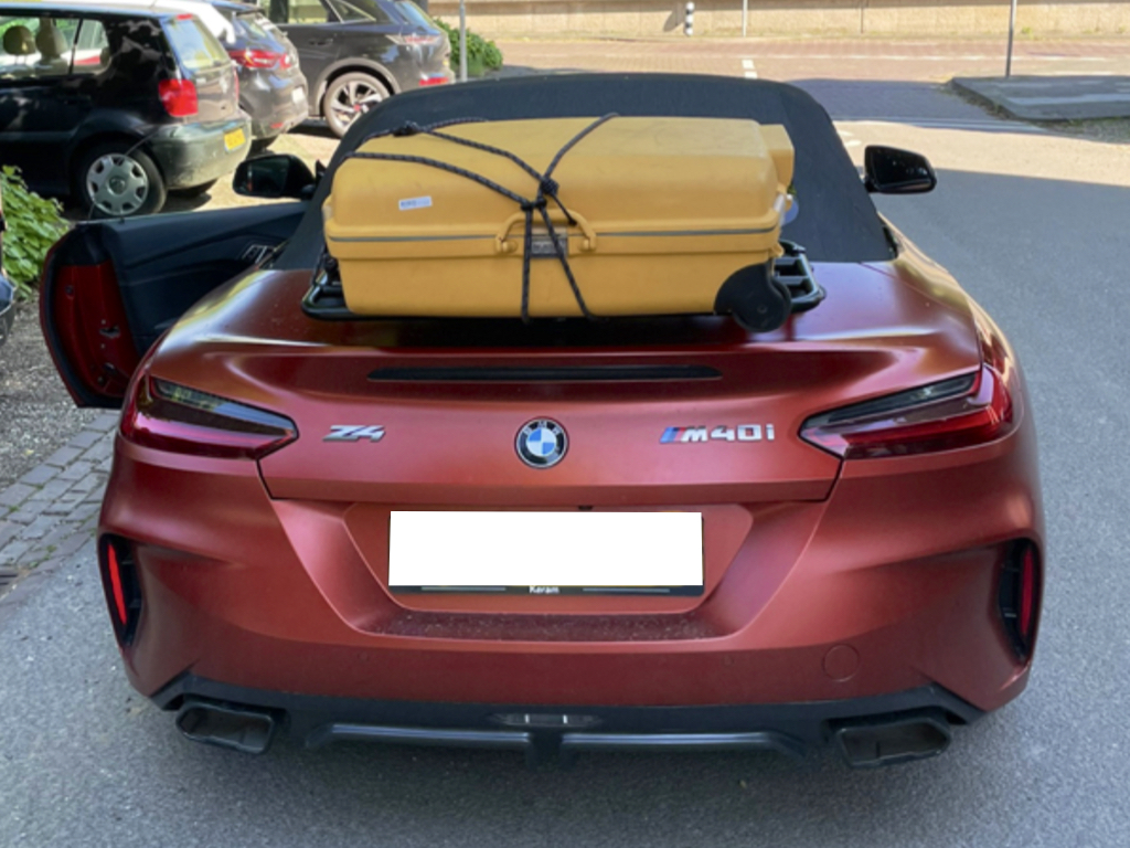 bronze bmw z4 g29 in a car park with a revo-rack luggage rack fitted carrying a yellow suitcase photographed from the rear 