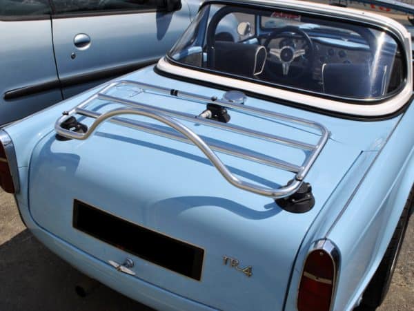 Light Blue Triumph TR4 with stainless steel luggage rack attached in the sunshine