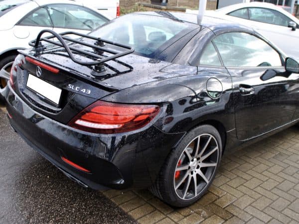 Black Mercedes SLC with black luggage rack attached on a rainy day