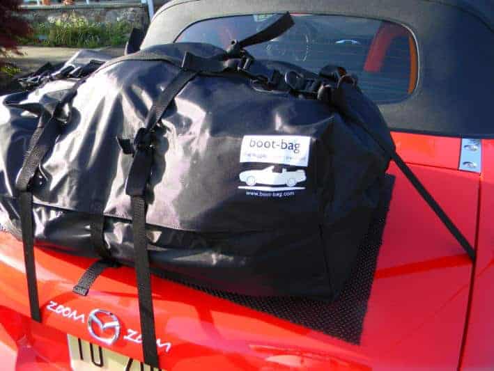 Red Mazda MX5 parked with hood up and boot bag luggage rack attached showing logo