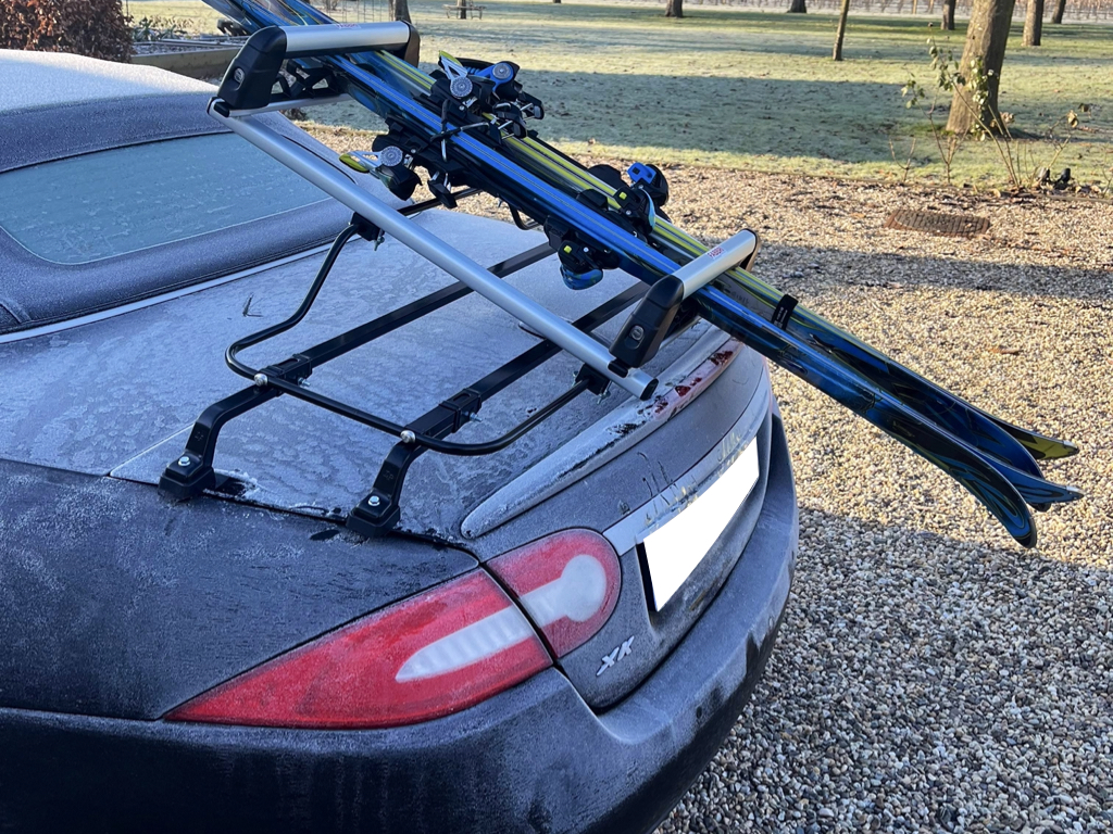 black jaguar xk convertible with a ski rack fitted carrying ski's photographed from the side covered in frost.